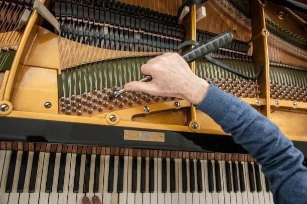 Piano tuner working on piano strings